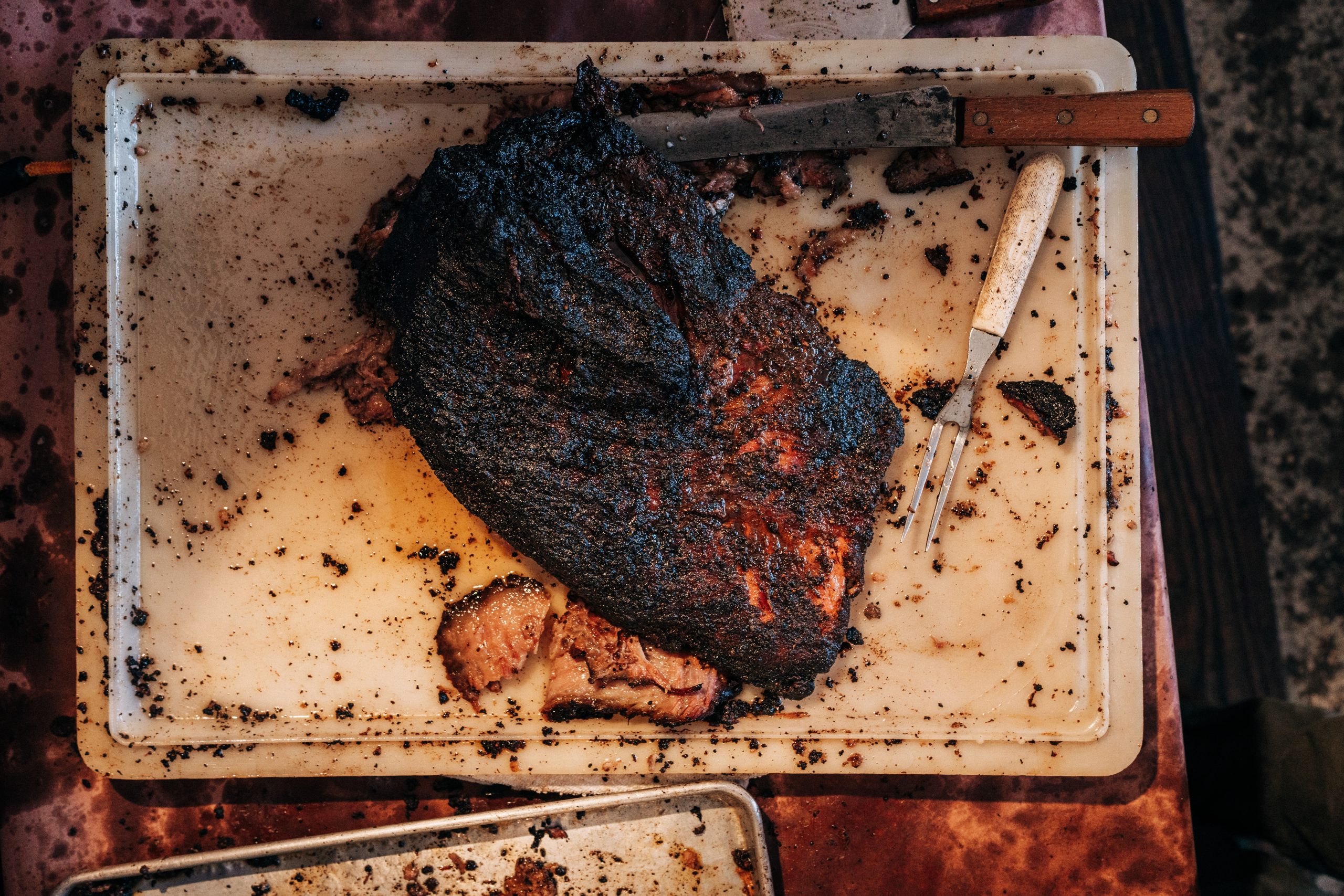 Overhead photo of brisket on a cutting board with knife lying to the side.