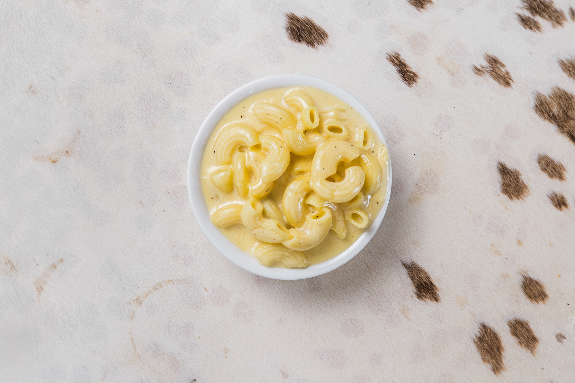 an overhead photo of a small bowl of mac’n cheese lying on a cowprint tablecloth.